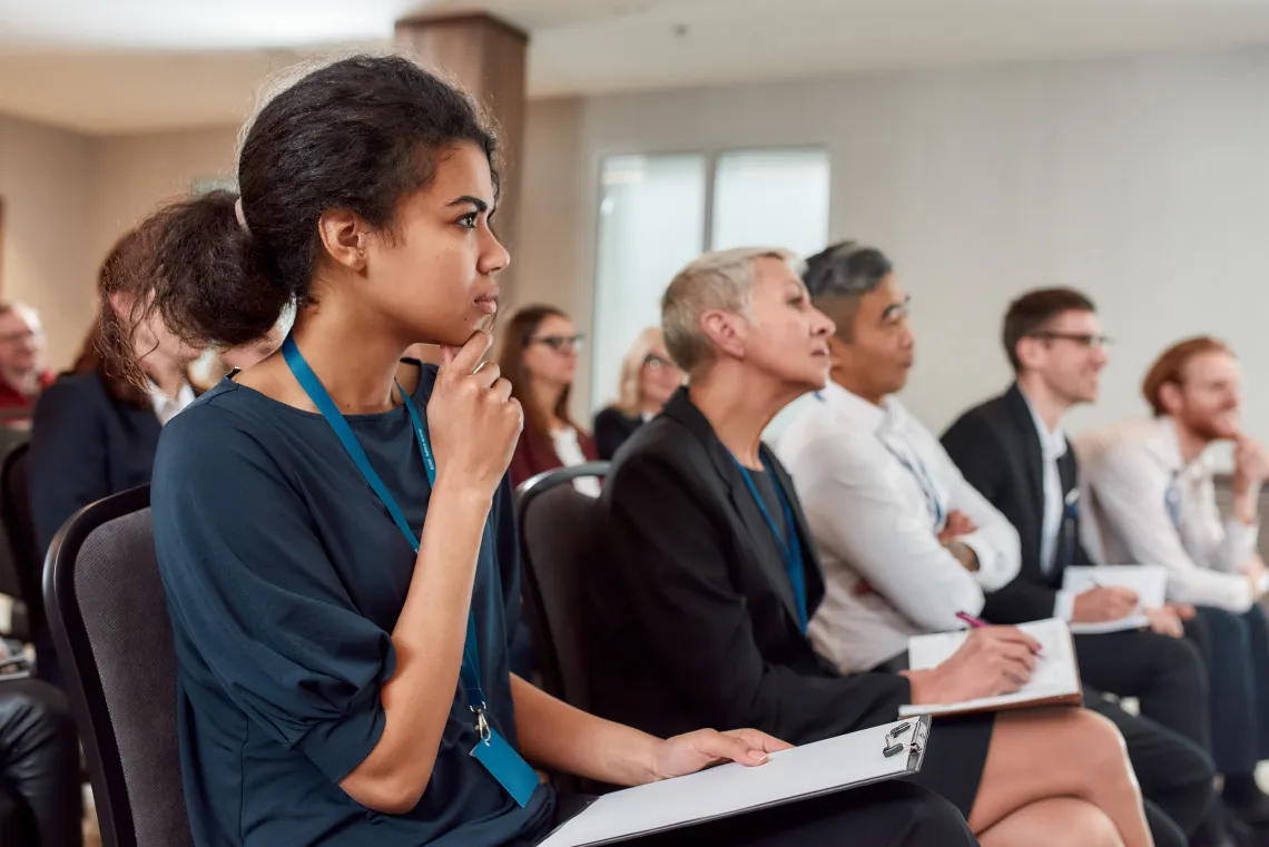 Audience sitting in a row while listening to presentation at conference hall